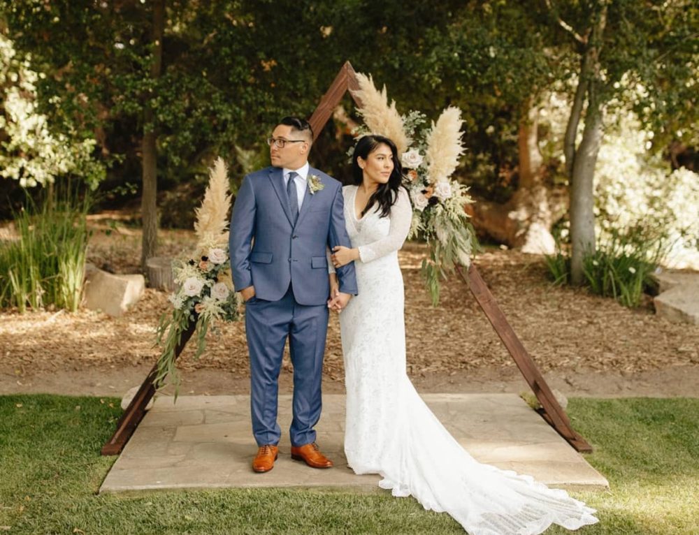 Bride and groom in front of triangle wedding arch